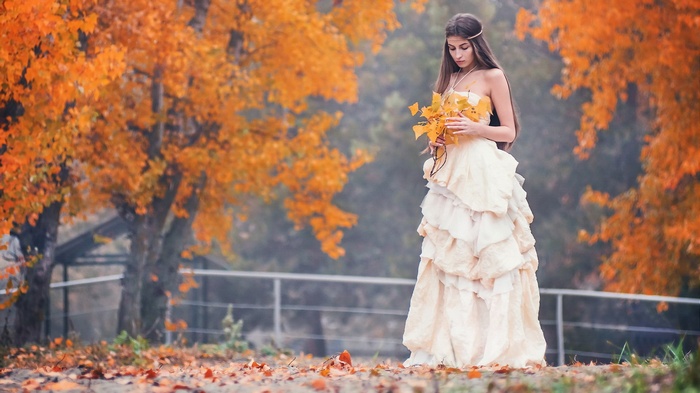 Woman in a dress holding leaves in autumn