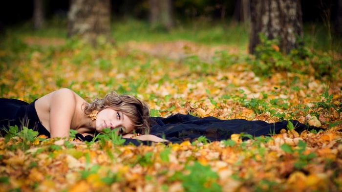 Woman lying on autumn leaves in a forest