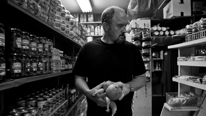 Louis C.K. holding fruit in a grocery store