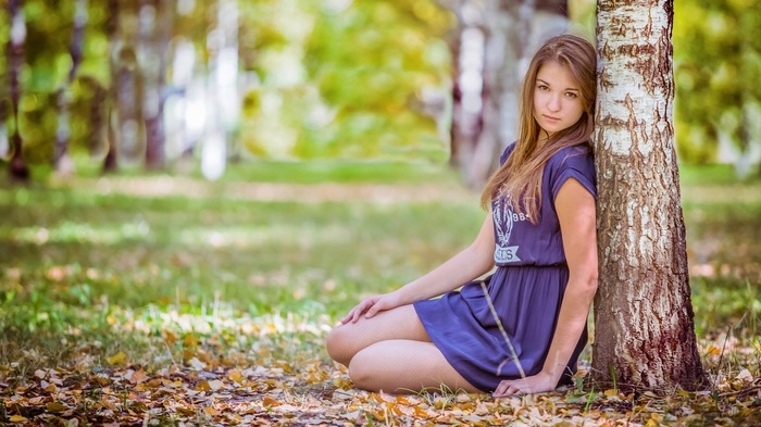 Girl leaning against a tree in a park