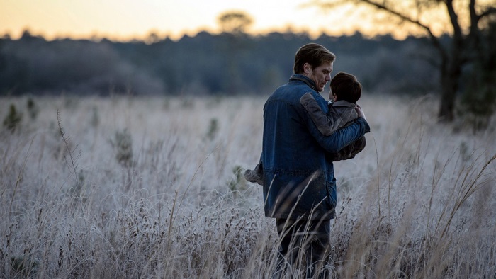 Michael Shannon holding a child in a field