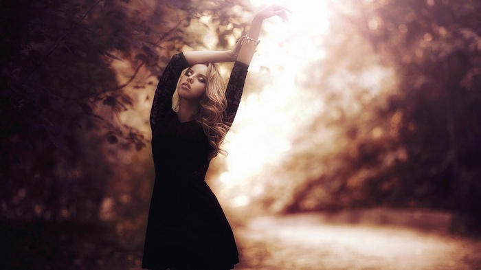 Woman in black dress with arms raised