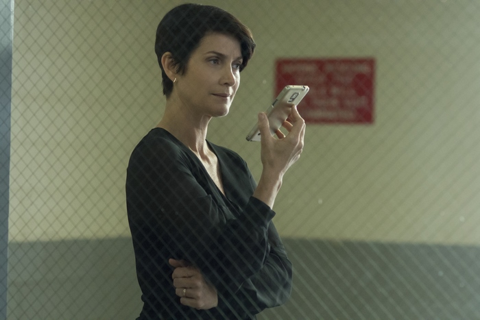 Carrie-Anne Moss holding a smartphone