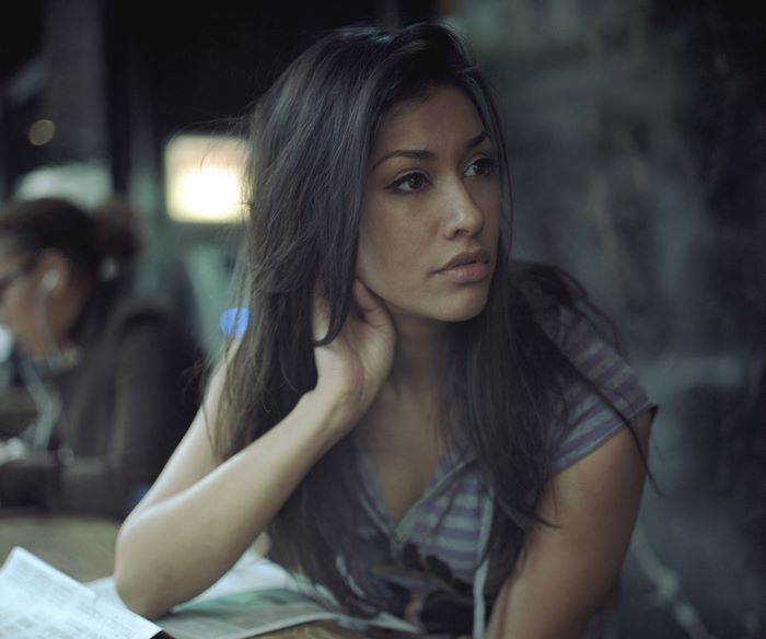 Janina Gavankar sitting at a table