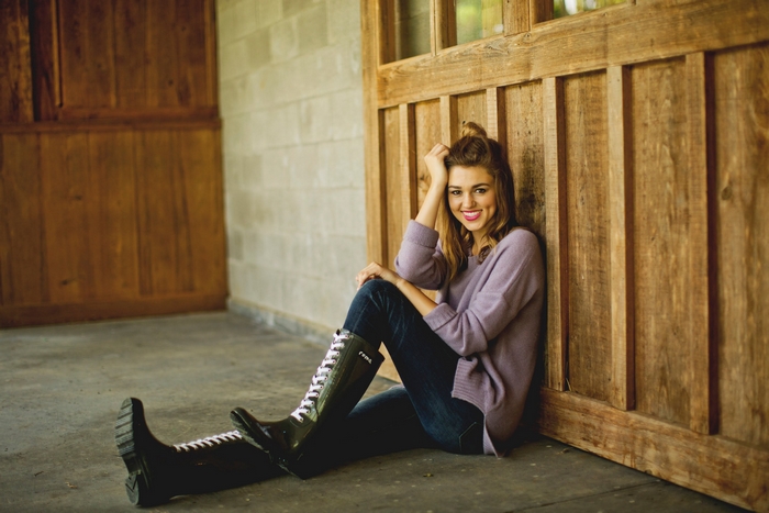 Sadie Robertson sitting by wooden wall