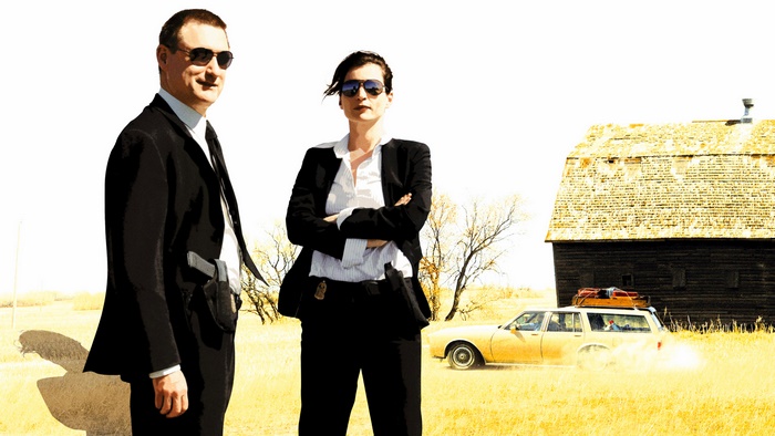 Bill Pullman and actress in suits with car and barn
