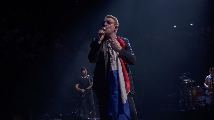 Bono from U2 holding a flag on stage