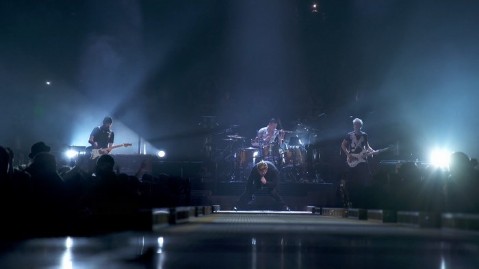 Bono performing on stage with a band