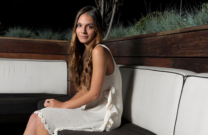 Caitlin Stasey sitting on a couch