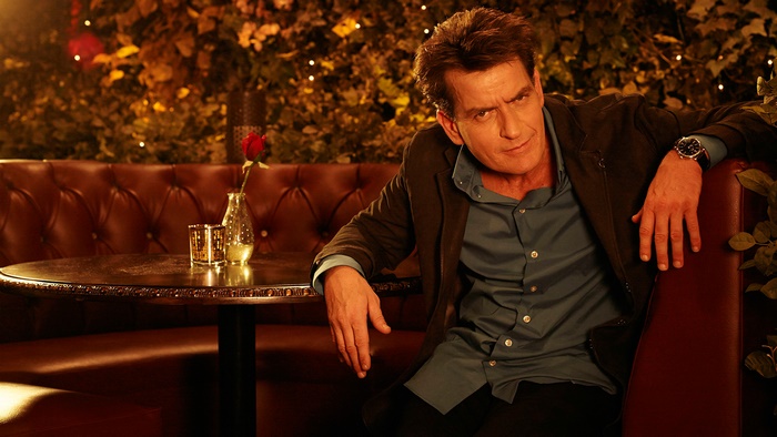 Charlie Sheen sitting in a booth