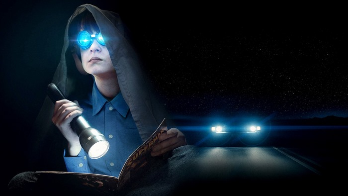 Jaeden Martell reading under a blanket with flashlight