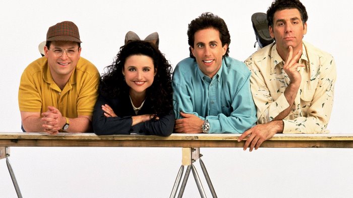 Seinfeld cast posing on a table