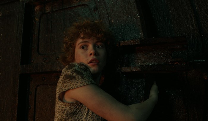 Sophia Lillis in a dark, metallic environment