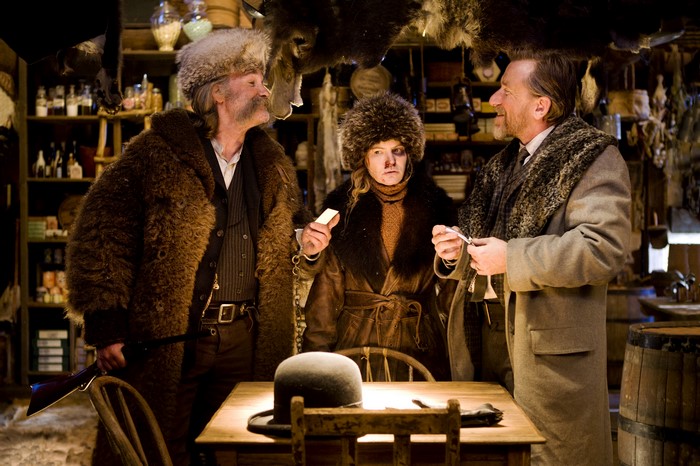Three people in fur coats in a rustic store