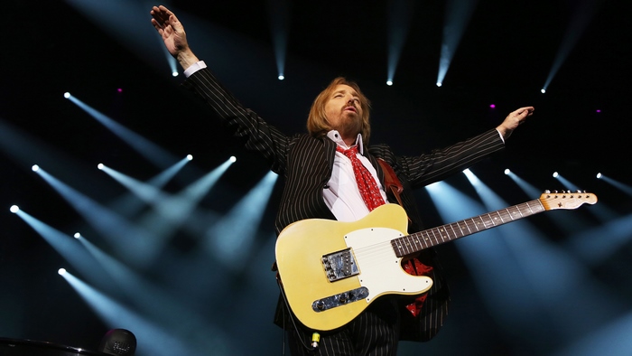 Tom Petty performing live on stage with guitar
