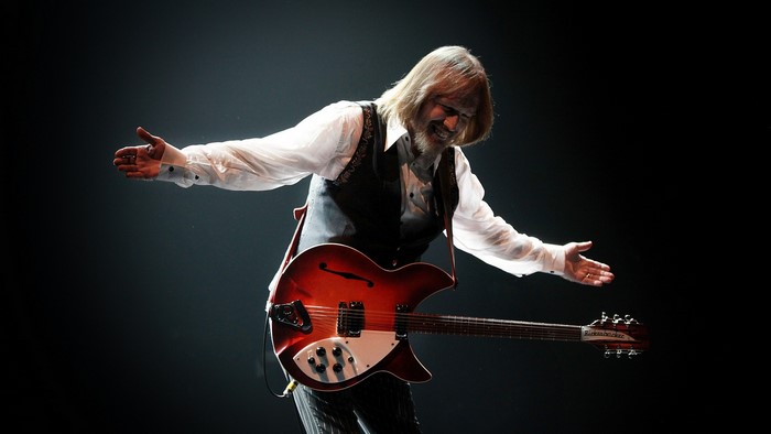 Tom Petty playing guitar on stage