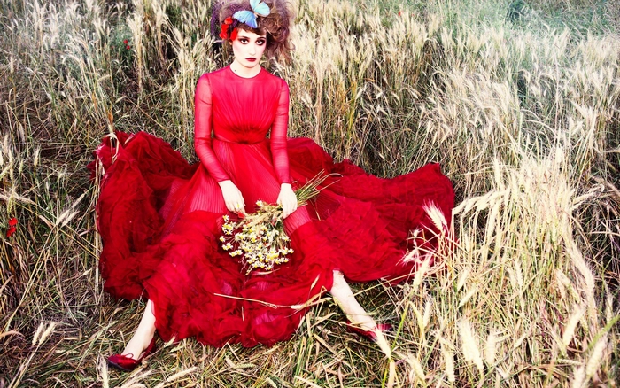 Déborah François in a red dress in a field