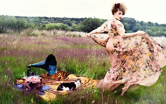 Déborah François in a floral dress with a gramophone and cat