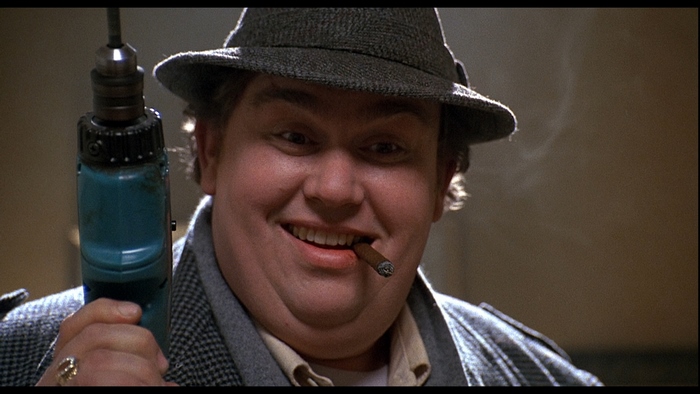 John Candy holding a drill and smoking a cigar