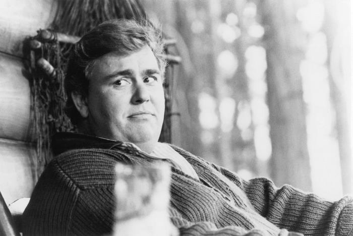 John Candy sitting in a chair
