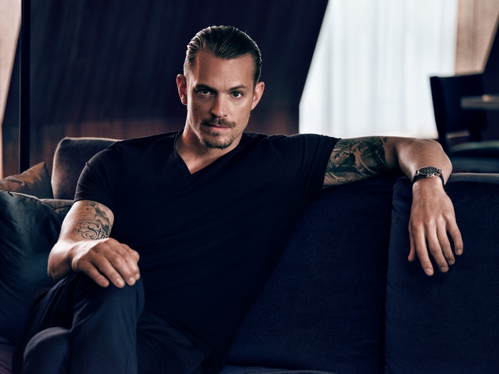 Joel Kinnaman sitting on a couch