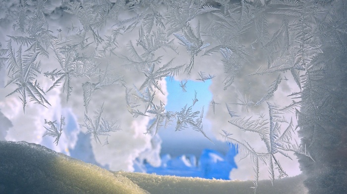 Frost patterns on a window with sky view
