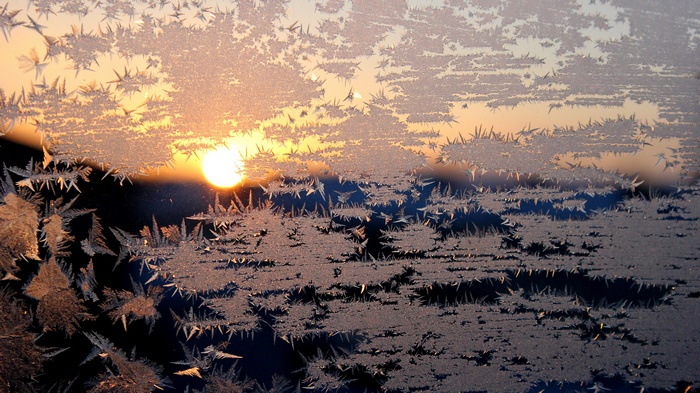 Frost patterns on a window with sunrise
