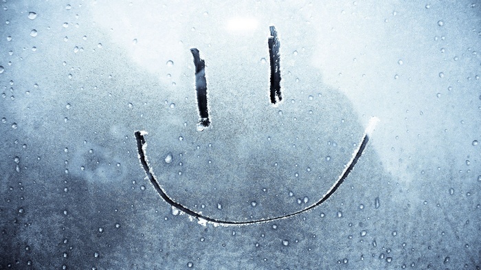 Smiley face drawn on a wet, frosted window