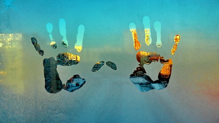 Handprints on a foggy window with city reflection