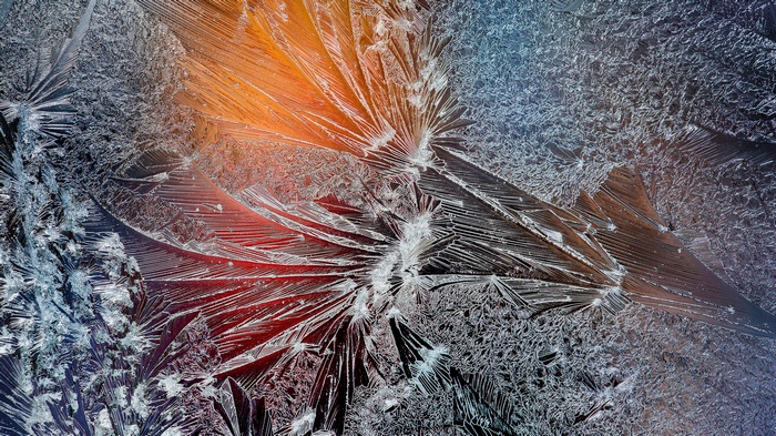 Close-up of frost patterns on glass with colored light