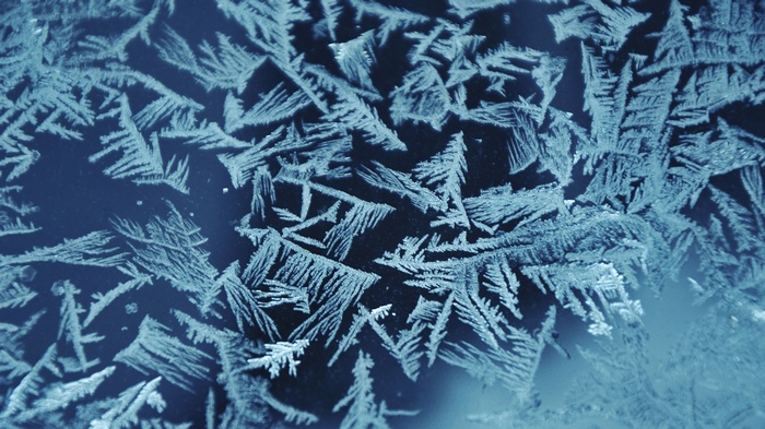 Close-up of frost patterns on a dark surface
