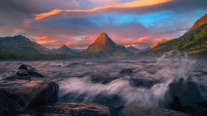 Sunset over mountains and lake with rocks