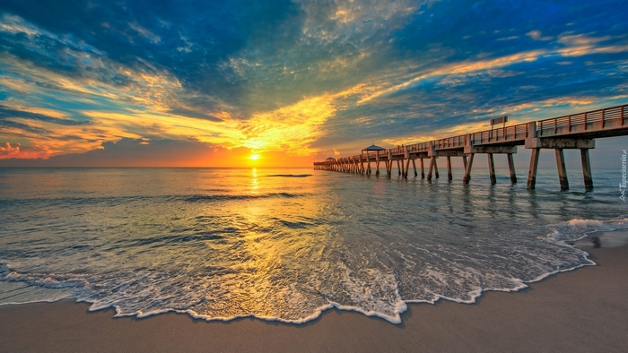 Ocean pier at sunset with dramatic sky