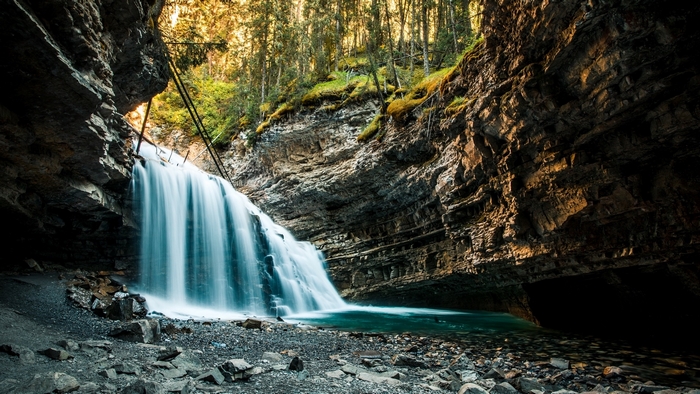 Waterfall cascading into a rocky gorge with forest above