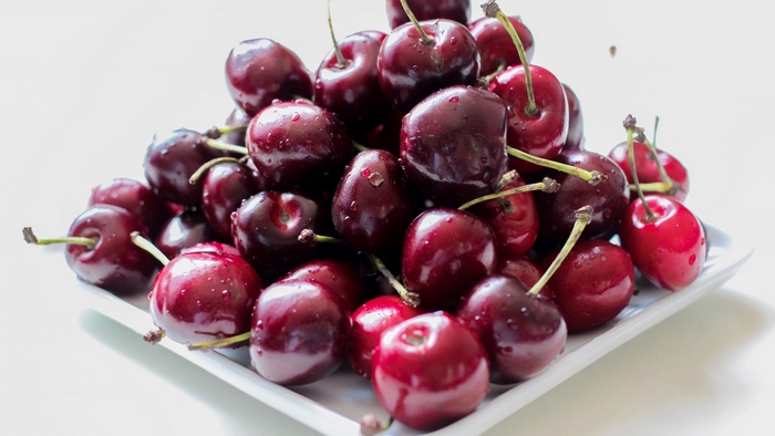 A pile of fresh cherries on a white plate