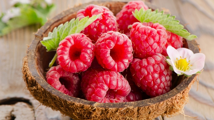 Raspberries in a coconut shell bowl with a flower