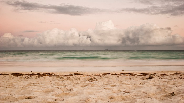 Beach with ocean waves and clouds at sunset