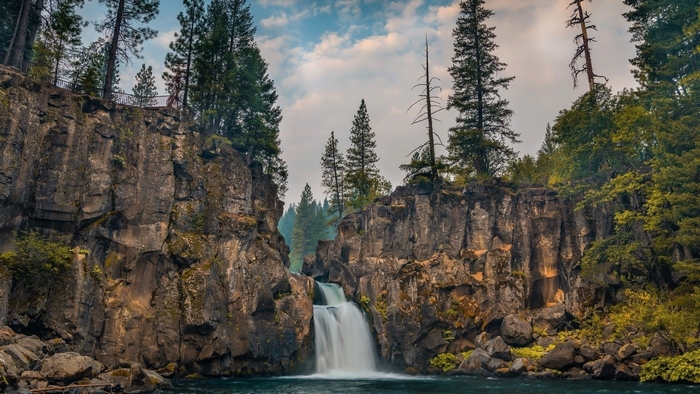 Waterfall cascading over rocky cliffs surrounded by trees
