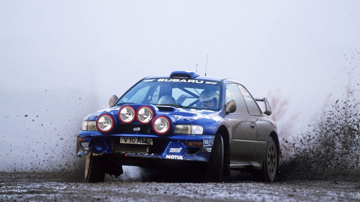 Blue Subaru Impreza rally car driving through dirt