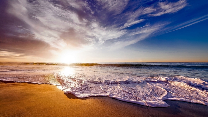 Sunset over the ocean with waves and clouds
