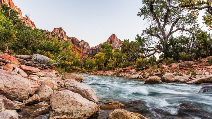 River flowing through a rocky landscape with trees and mountains