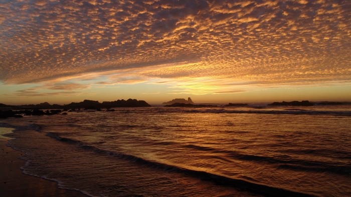 Sunset over the ocean with clouds and waves