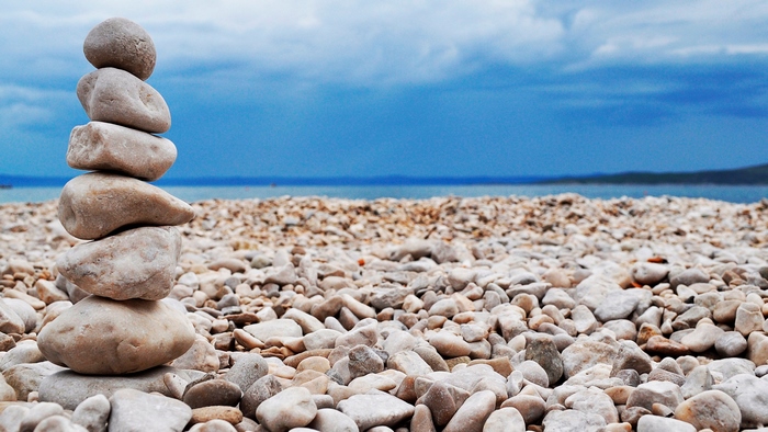 Stacked stones on a pebble beach with blue sky