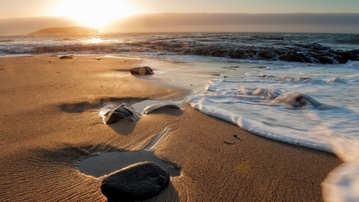 Beach with sunrise and waves crashing on shore