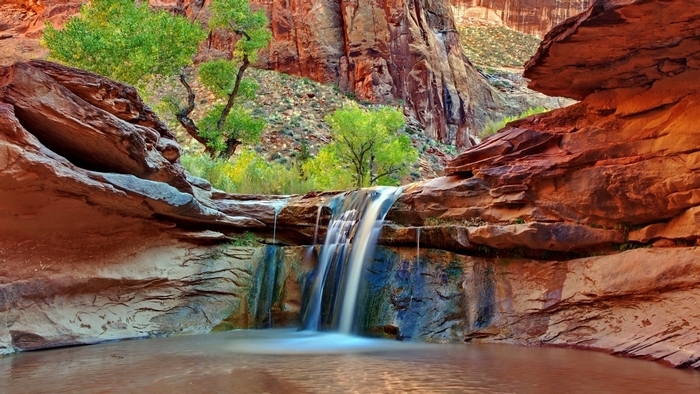 Waterfall cascading into a pool in a rocky canyon
