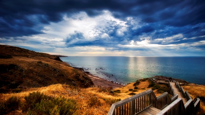 Stormy Coastal Path with Sunrays Over Ocean