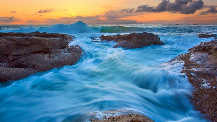 Ocean waves crashing on rocks at sunset