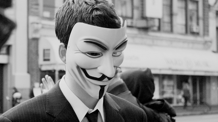 Person wearing a Guy Fawkes mask and suit