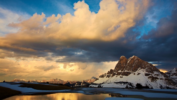 Snow-capped mountains reflected in a lake at sunset