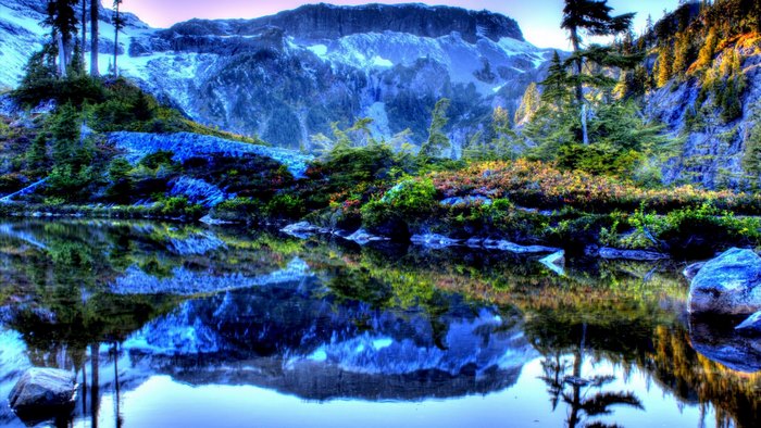Mountain lake reflection with trees and snow